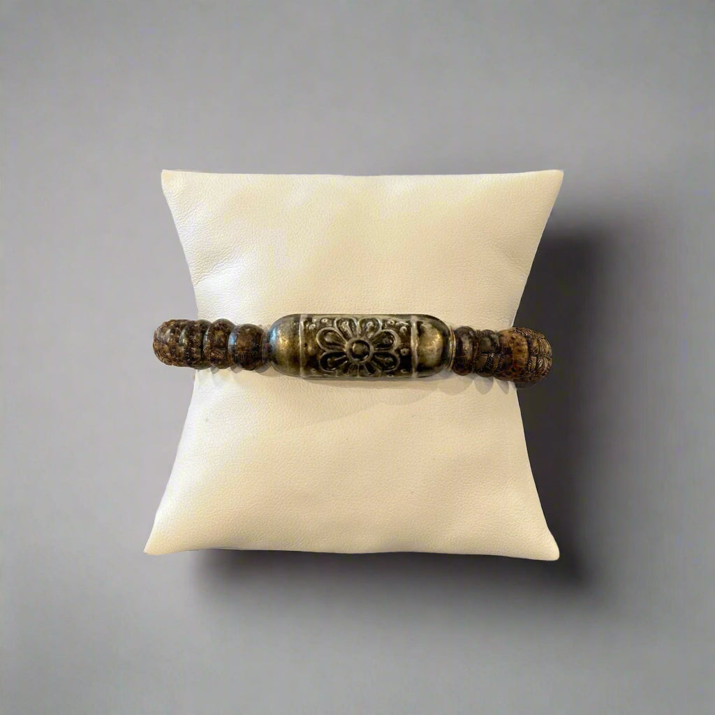A bracelet with dark and light brown wooden beads on a white pillow.