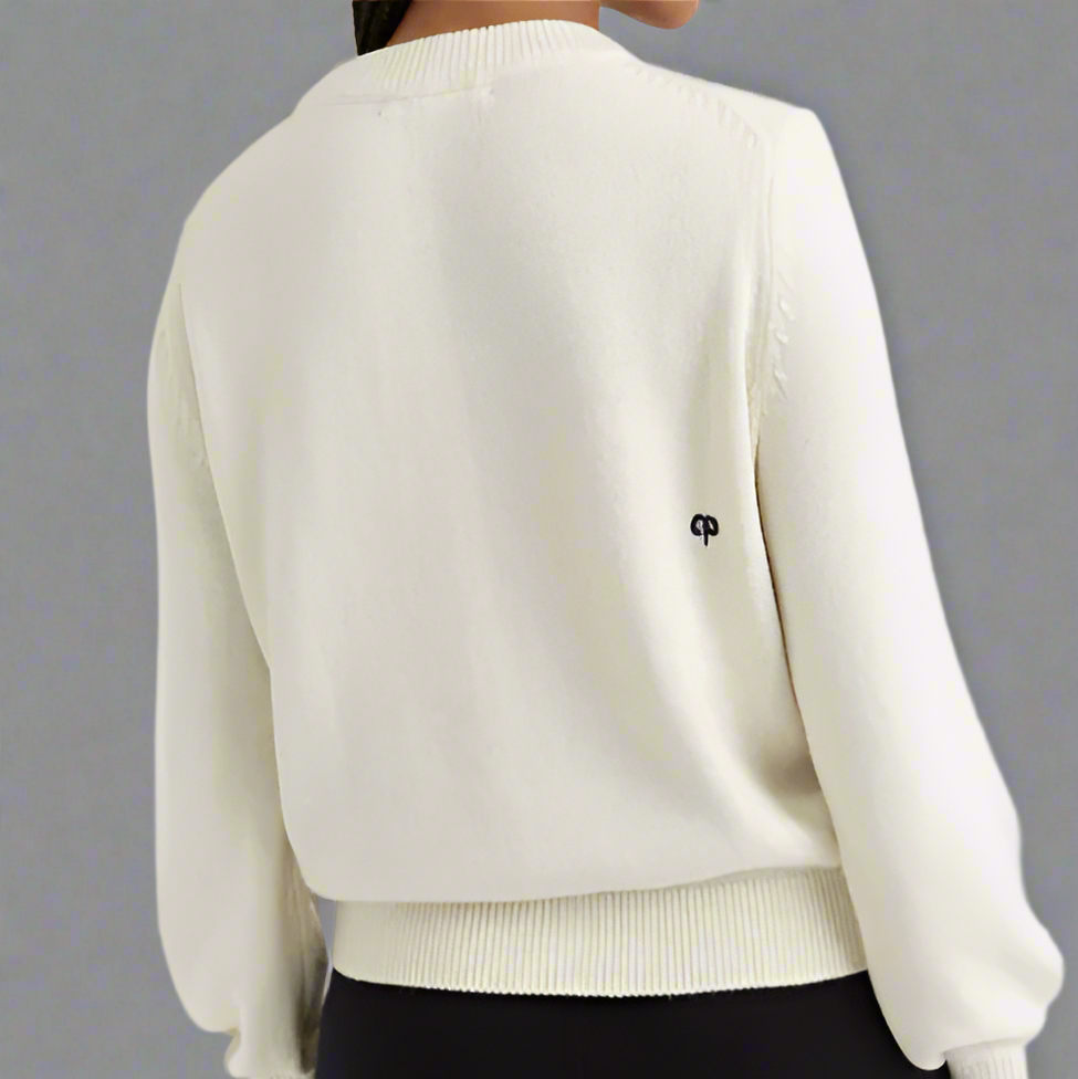 White sweater with a small logo on a plain background