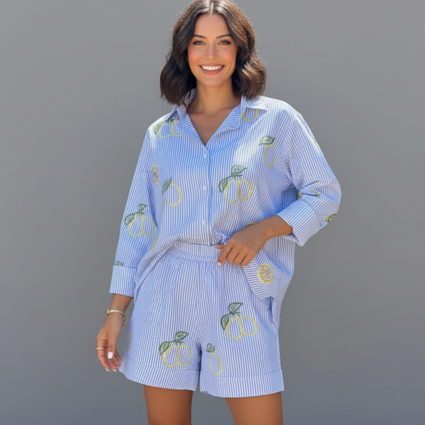 Woman wearing a blue and white striped pajama set with lemon designs on a gray background