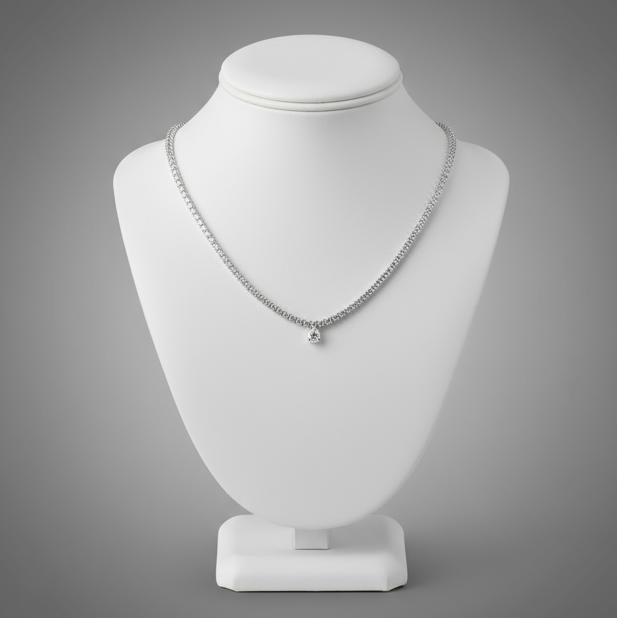 Silver necklace on a white mannequin bust against a gray background