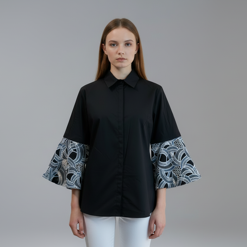 Black shirt with patterned sleeves on a mannequin against a white background