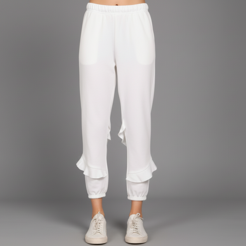 A person standing wearing purple ruffle sweatpants and white sneakers.