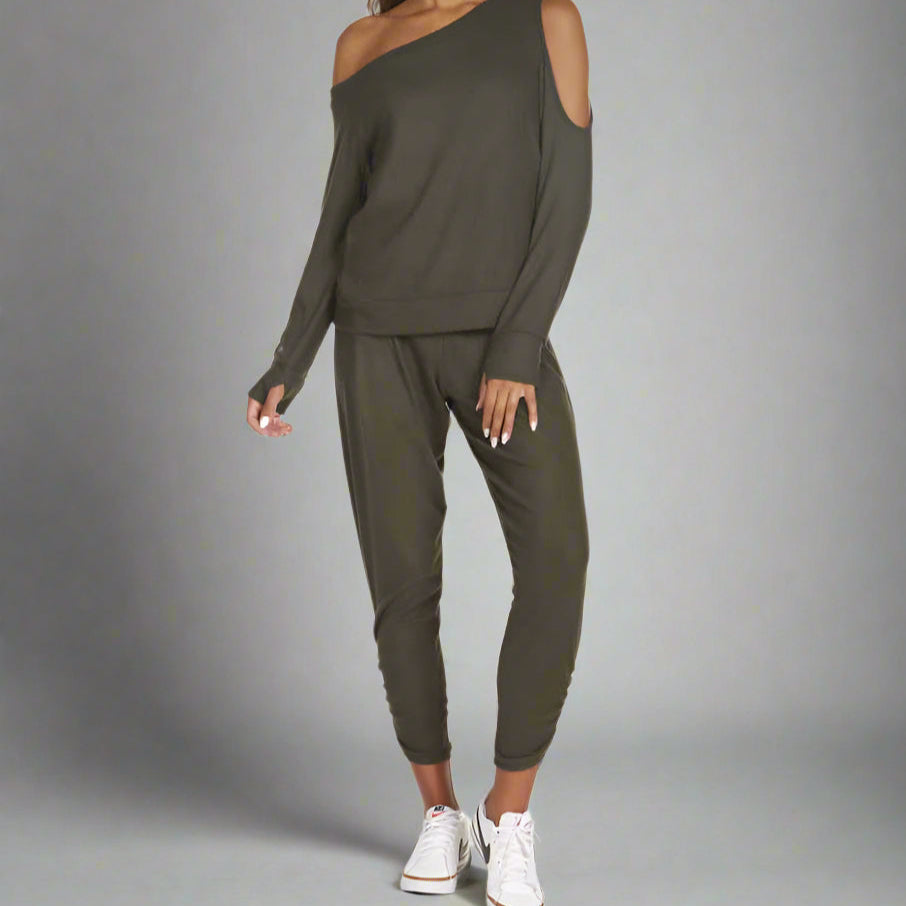 A female model wearing a green cold shoulder top and matching pants.
