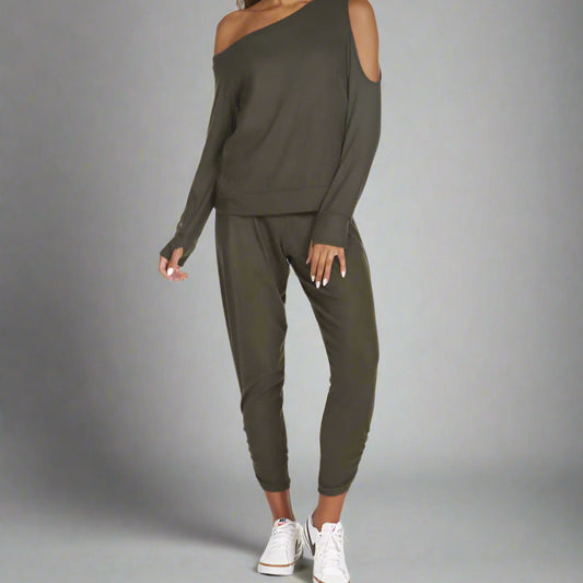 A female model wearing a green cold shoulder top and matching pants.