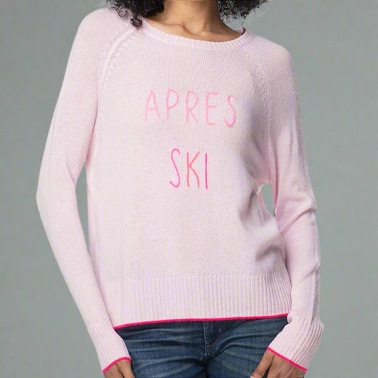 Pink sweater with 'APRES SKI' text worn by a person on a gray background