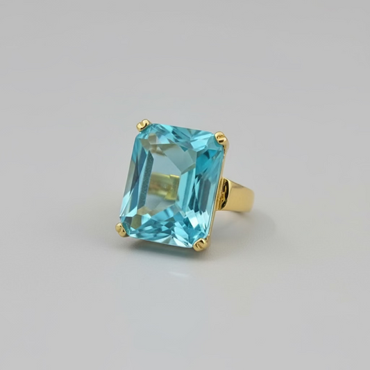 Small blue gemstone on a white stand on a desk with a laptop in the background