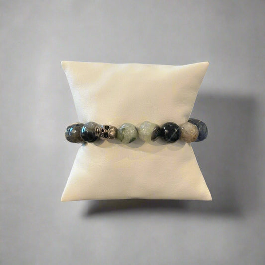 A bracelet with a mix of blue agate and pearl beads, displayed on a white cushion.