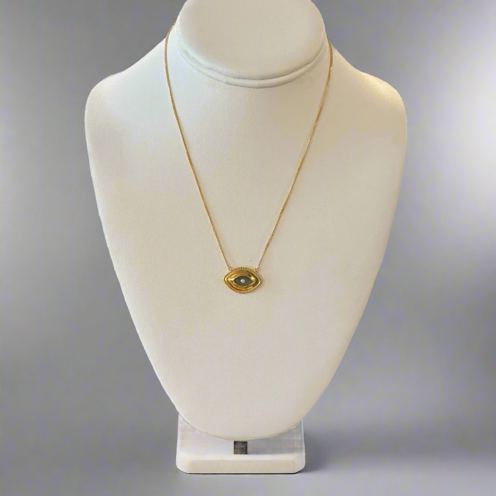 A gold-colored necklace with a central labradorite eye-shaped pendant displayed on a white mannequin bust.