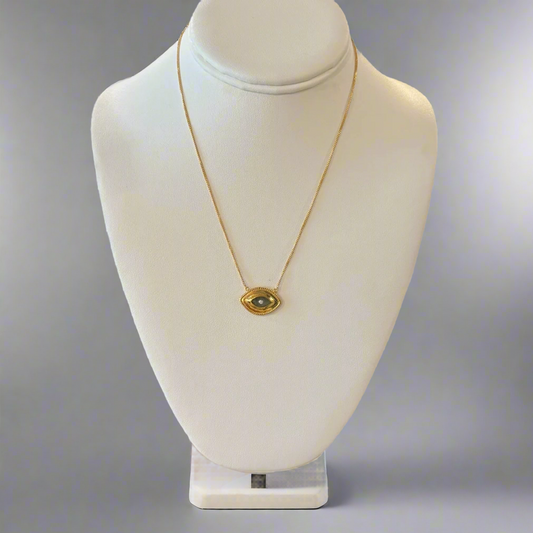 A gold-colored necklace with a central labradorite eye-shaped pendant displayed on a white mannequin bust.
