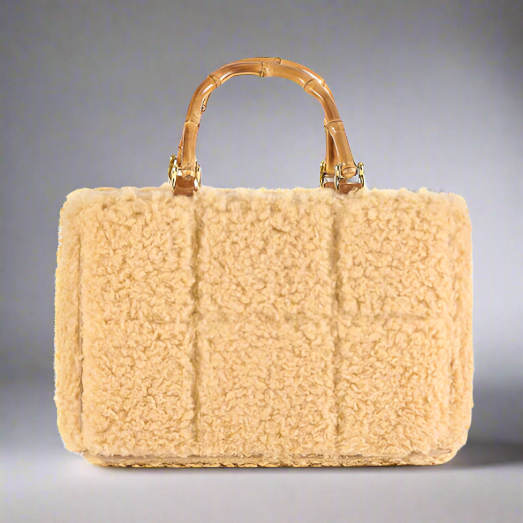 Beige shearling handbag with bamboo handle on a white background