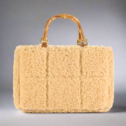 Beige shearling handbag with bamboo handle on a white background