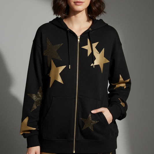 A black hoodie with gold crystal star appliques, featuring a front zipper and a split kangaroo pocket. The hoodie is cropped to show the length and features a dropped shoulder design.