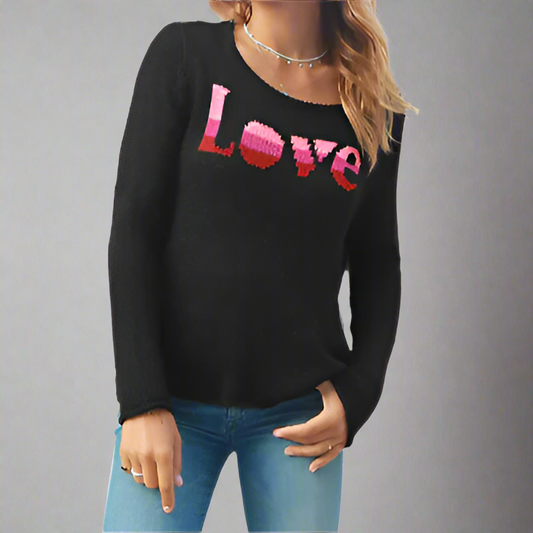 A woman wearing a black crew neck sweater with the word 'Love' knitted in the center front, in shades of pink and red.