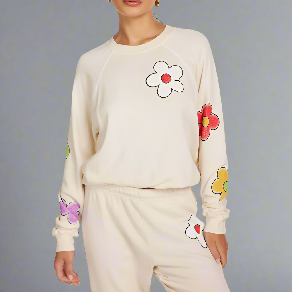 Woman wearing a cream-colored sweatshirt with colorful flower designs on a white background