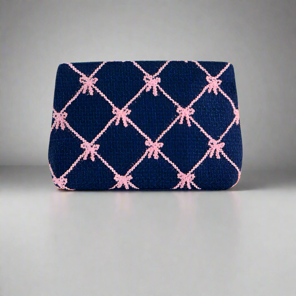 Navy clutch bag with pink bow pattern on a white background